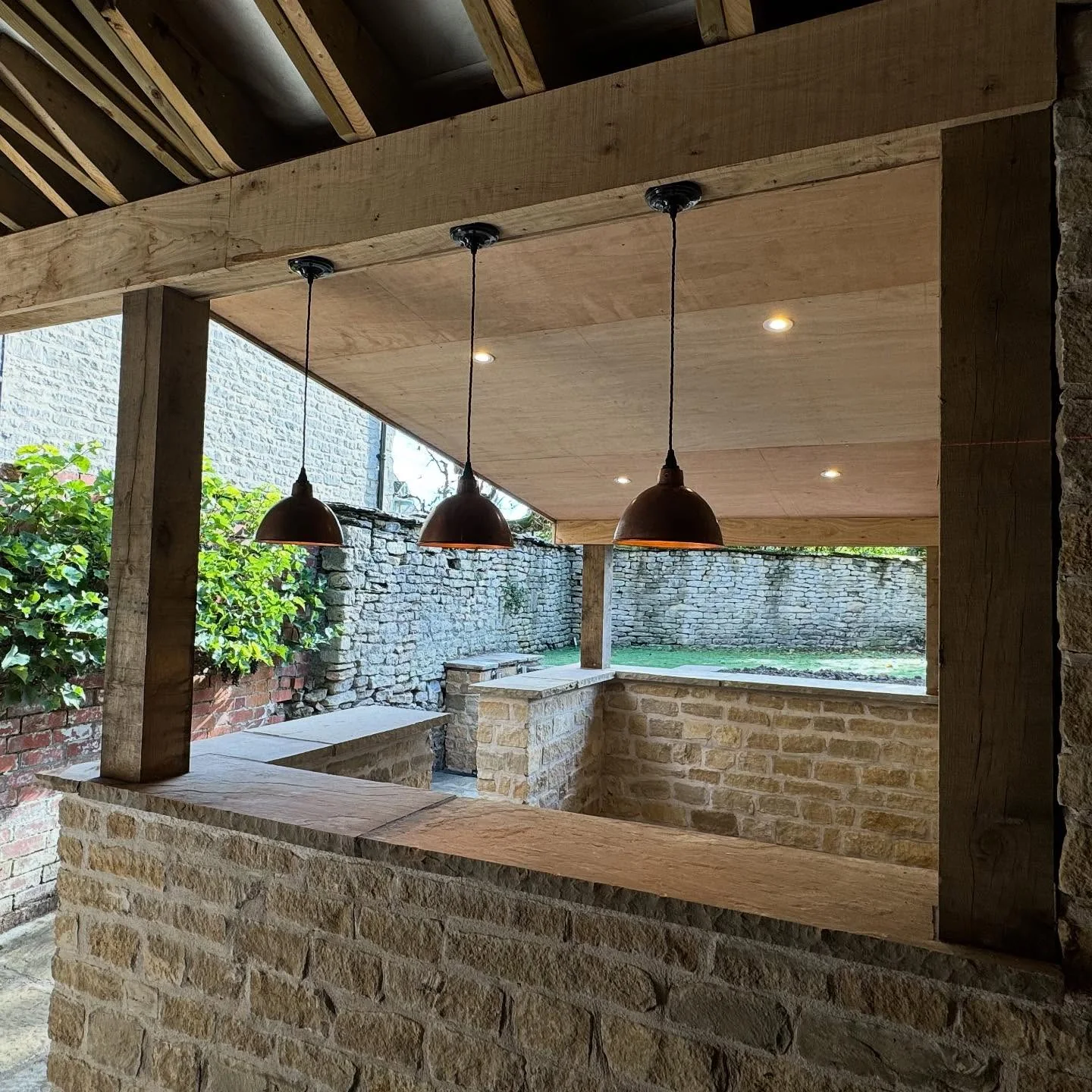 Pendant and recessed lights in a timber-framed stone patio