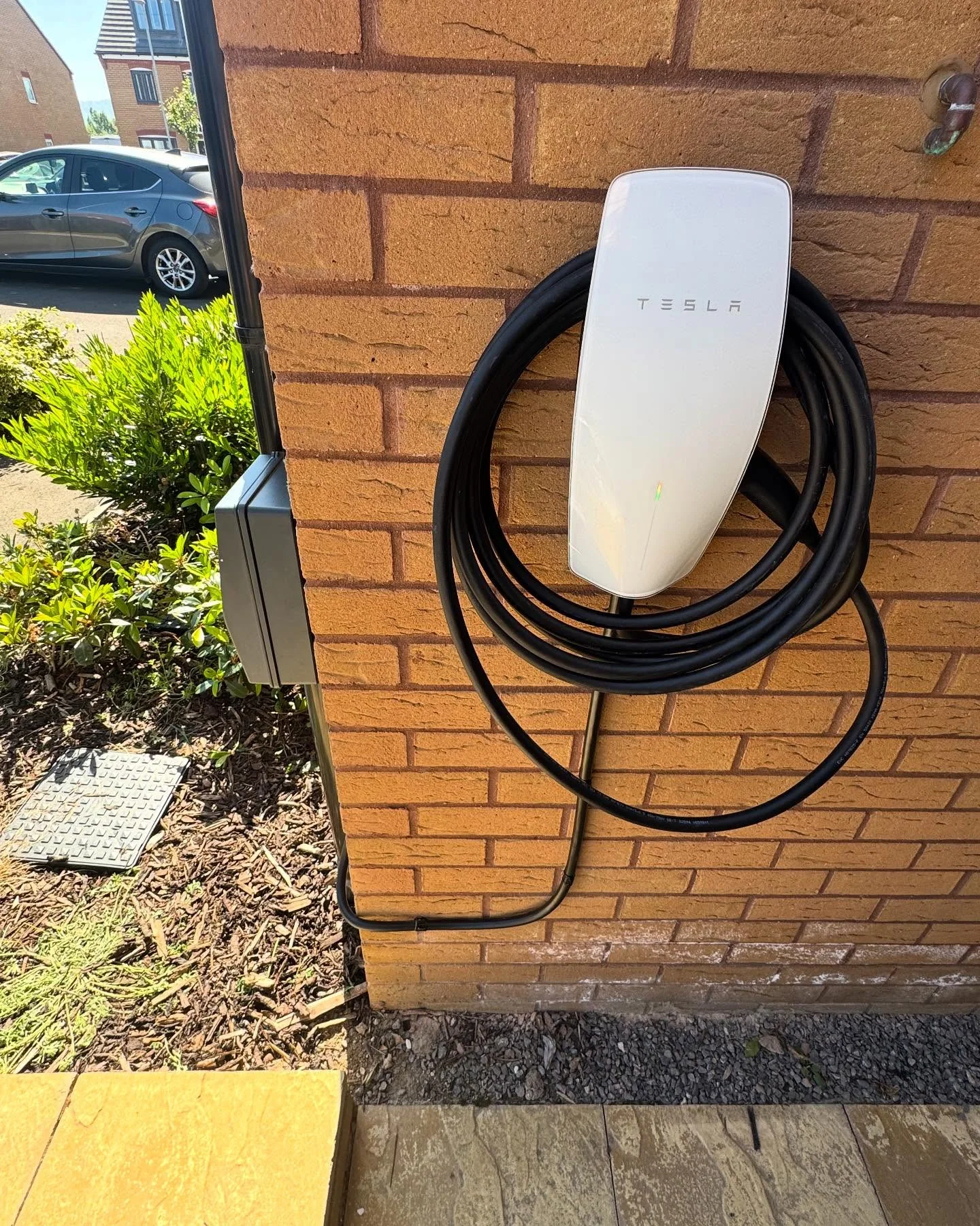 Tesla electric vehicle charger installed on a brick wall